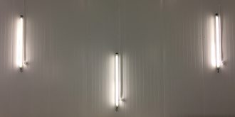 Three fluorescent lamps mounted vertically on the wall